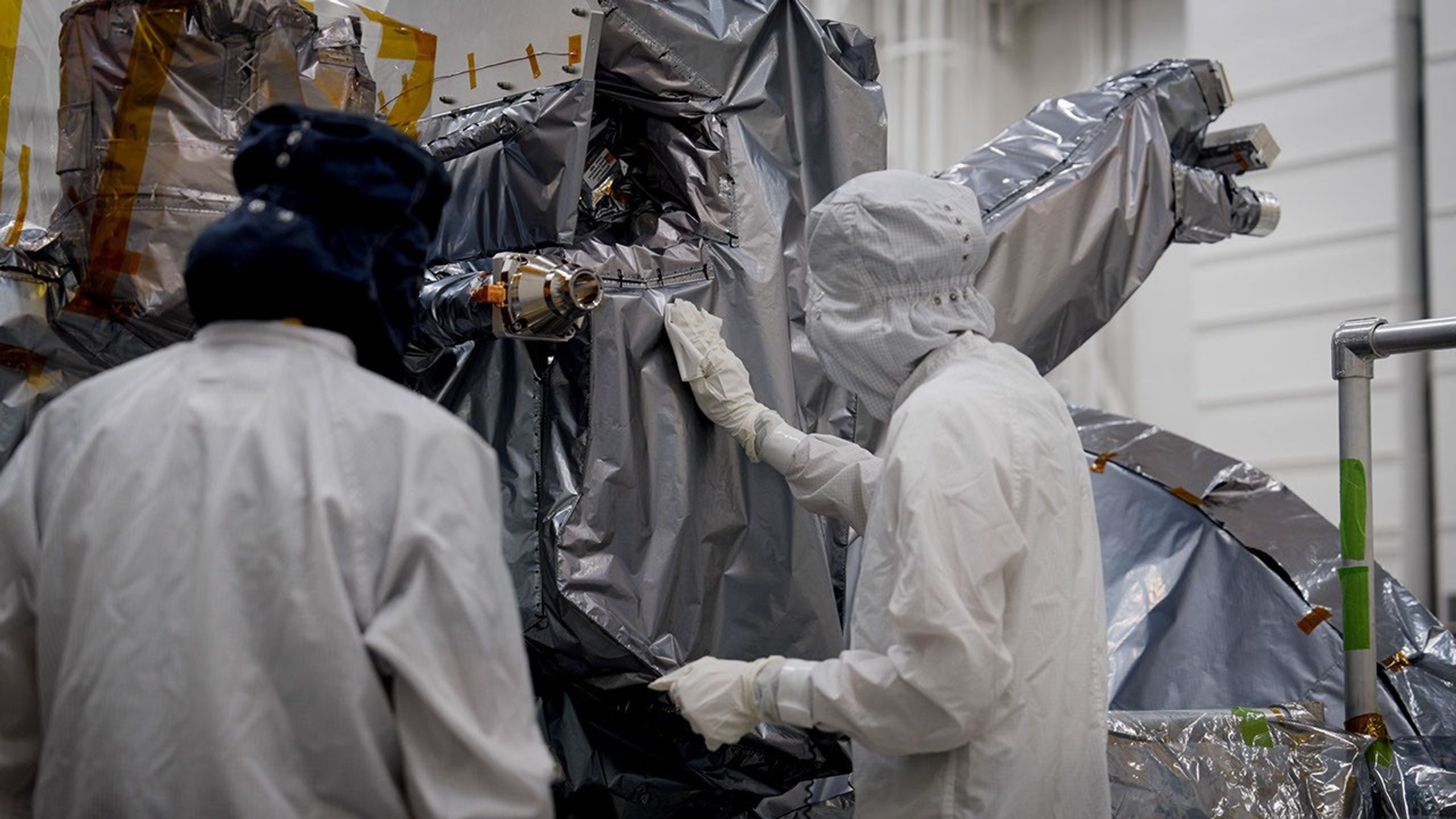 Engineers in a clean room inspecting the Europa Clipper spacecraft.